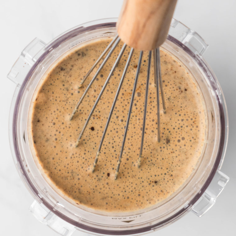 Whisking chilled coffee, milk, and chocolate syrup together in a glass pitcher