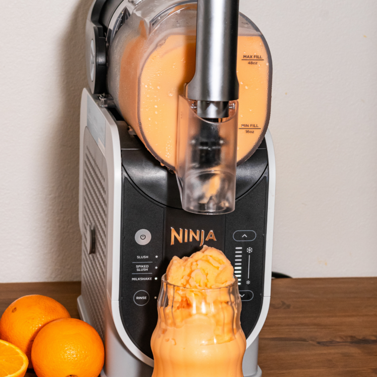 Frothy Orange Julius slush dispensing from the Ninja Slushi into a chilled glass