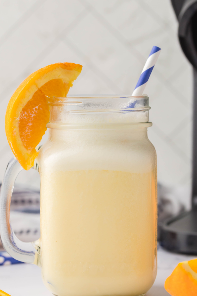 Creamy frozen Ninja Slushi Orange Julius in a glass with a frothy top and straw