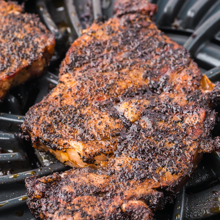 Cooked bone-in Outlaw Ribeye steak on a plate with a dark seared crust