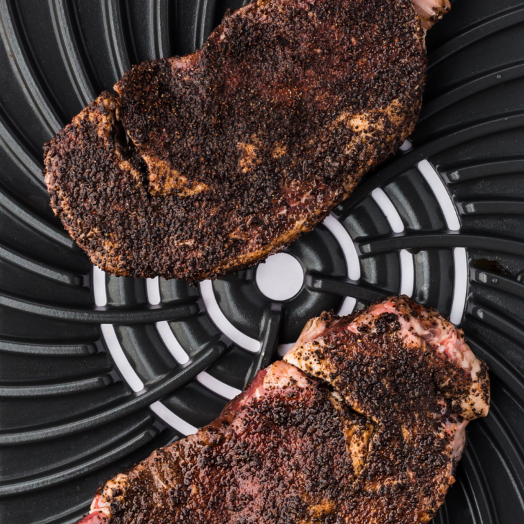 Outlaw Ribeye searing in a hot pan, forming a deep dark crust on one side