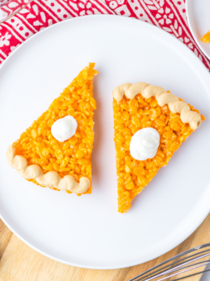 Pumpkin pie Rice Krispie treat slice topped with a cream cheese dollop and piped peanut butter crust