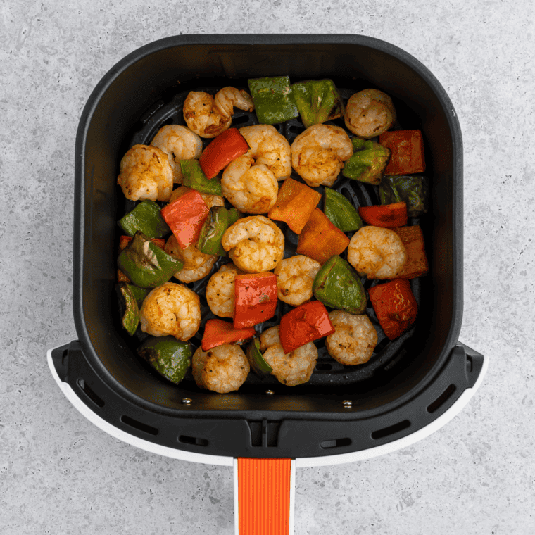 Cooked shrimp coated in Red Lobster Cajun seasoning in an air fryer basket