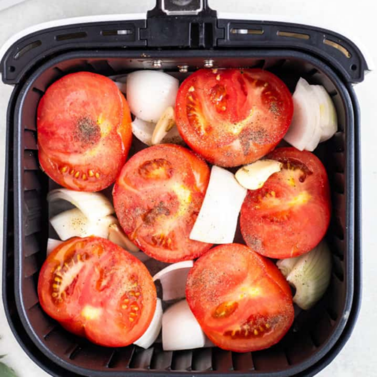 Halved roma tomatoes, quartered onion and whole garlic cloves tossed with olive oil in an air fryer basket