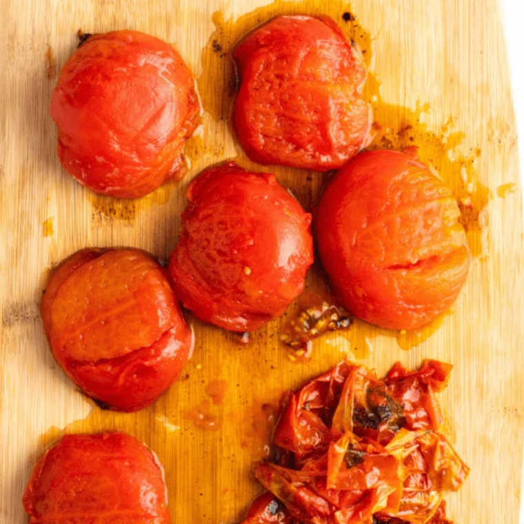 Roasted roma tomatoes, onion and garlic tipped from an air fryer basket into a glass bowl