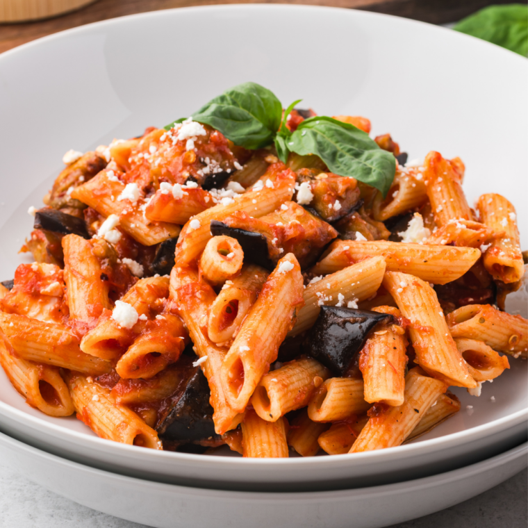 Roasted tomato pasta sauce over spaghetti in a white bowl, topped with parmesan and fresh basil