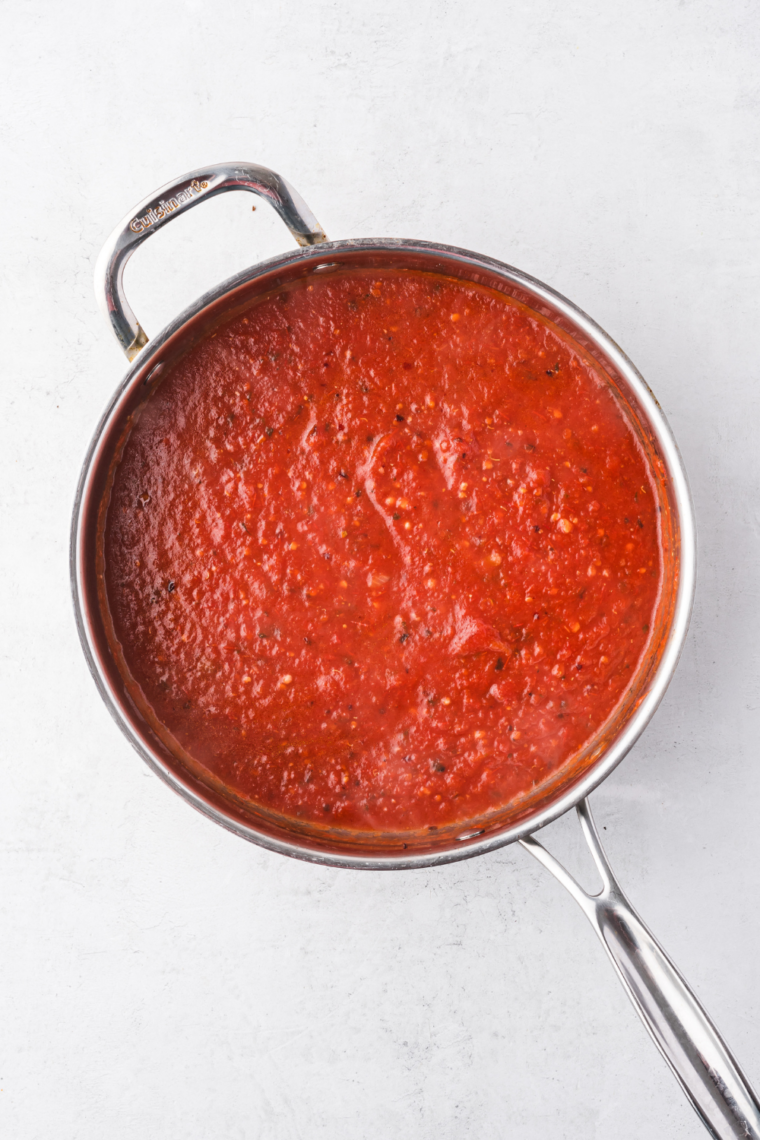 Overhead bowl of spaghetti tossed in roasted tomato pasta sauce with basil leaves and a fork