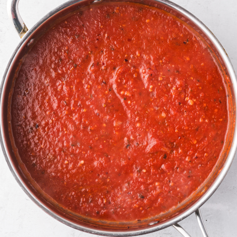Immersion blender pureeing roasted roma tomatoes into a smooth red sauce