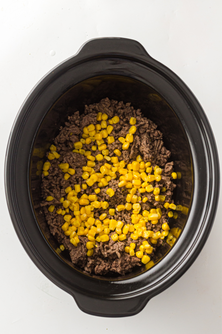 Ground beef, corn, cheese, and creamy soup stirred together in a slow cooker insert