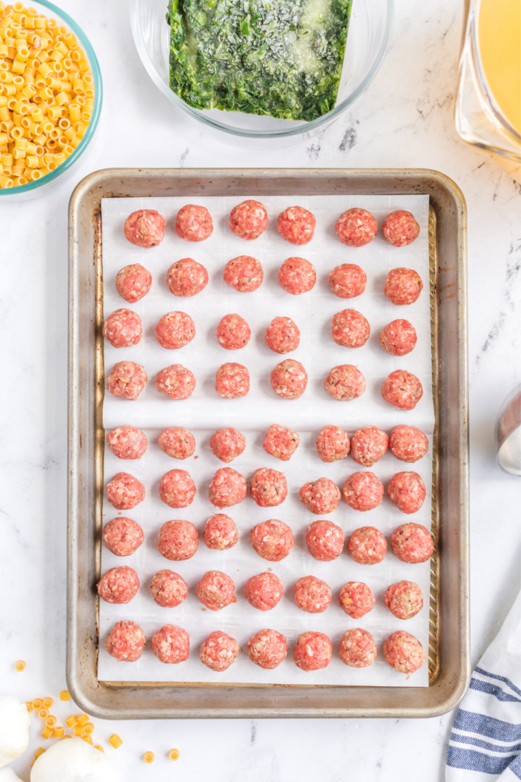 Chicken meatballs roasting on a parchment-lined sheet pan at 400 degrees