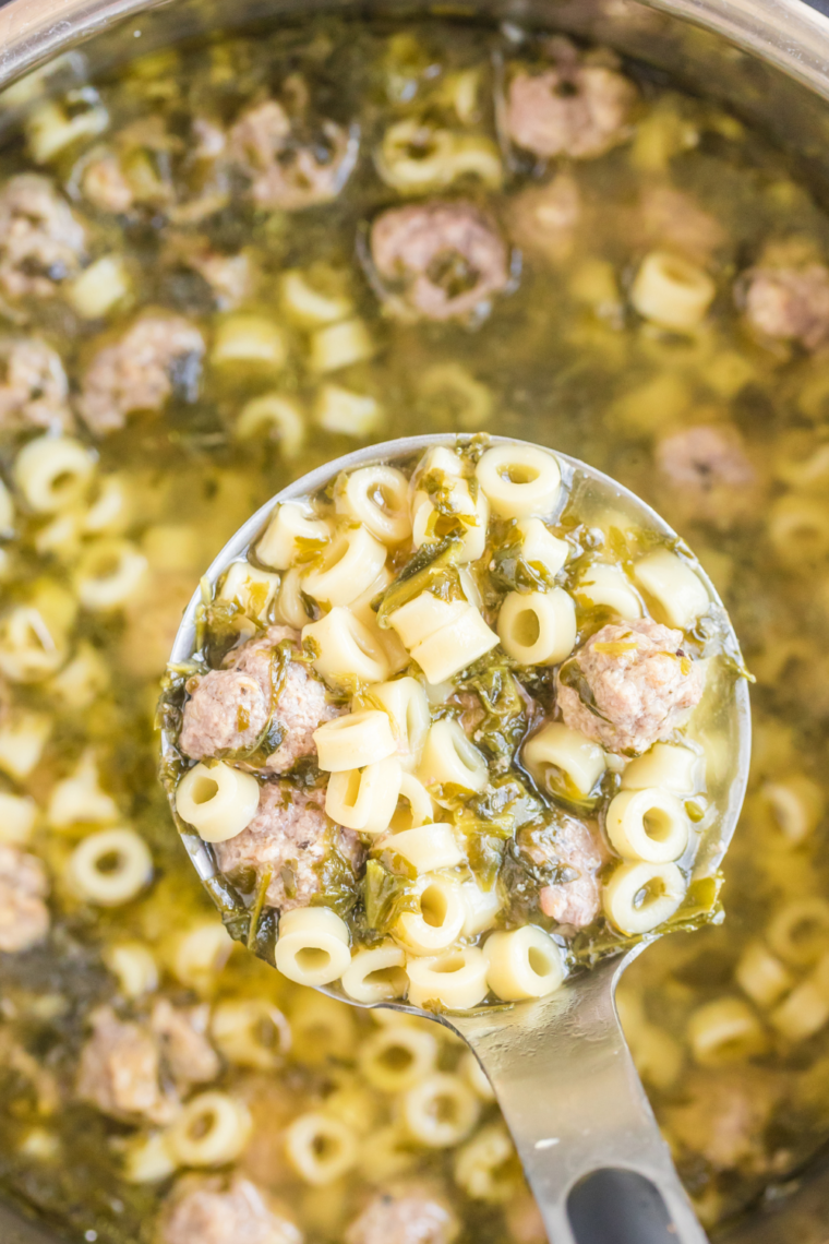 Overhead view of Italian wedding soup in a slow cooker with meatballs, carrots, and baby spinach