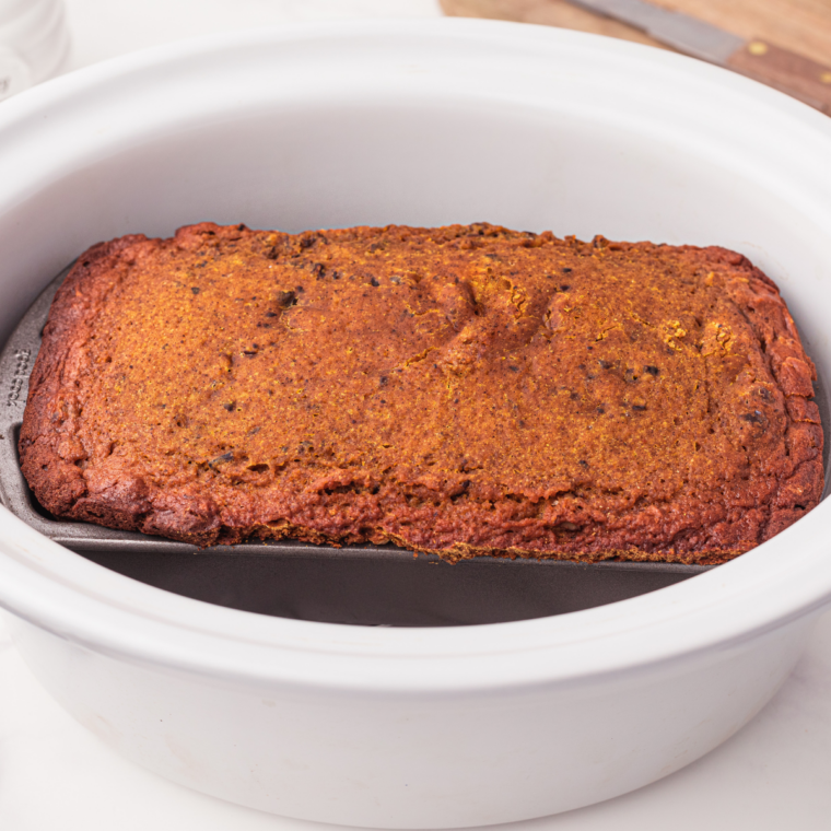 Instant read thermometer showing 202 degrees inserted into the center of slow cooker pumpkin bread