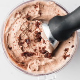 Two scoops of Cold Stone Chocolate Devotion Ninja Creami ice cream topped with brownie pieces and a hot fudge drizzle