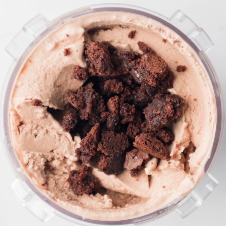 Brownie chunks, chocolate chips, and hot fudge added to a well in the Ninja Creami chocolate ice cream before the Mix-In cycle