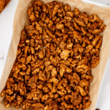 Air fryer candied coffee walnuts cooling in a single layer on a parchment-lined baking sheet