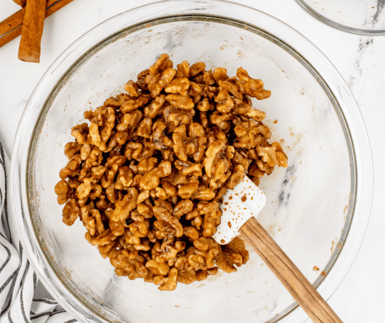 Raw walnuts coated in a wet coffee-sugar mixture in a bowl