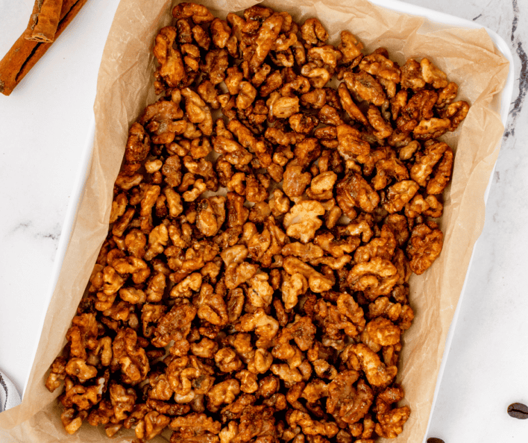 Air fryer candied coffee walnuts cooling in a single layer on a parchment-lined baking sheet