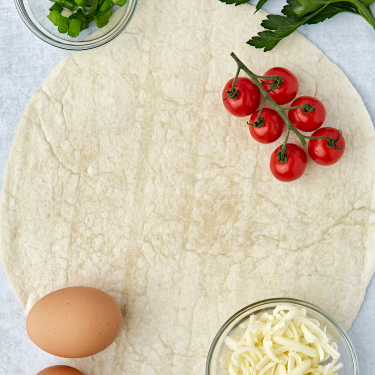 Ingredients for air fryer egg tortilla frittata: flour tortilla, eggs, milk, shredded cheese, bell pepper, and red onion
