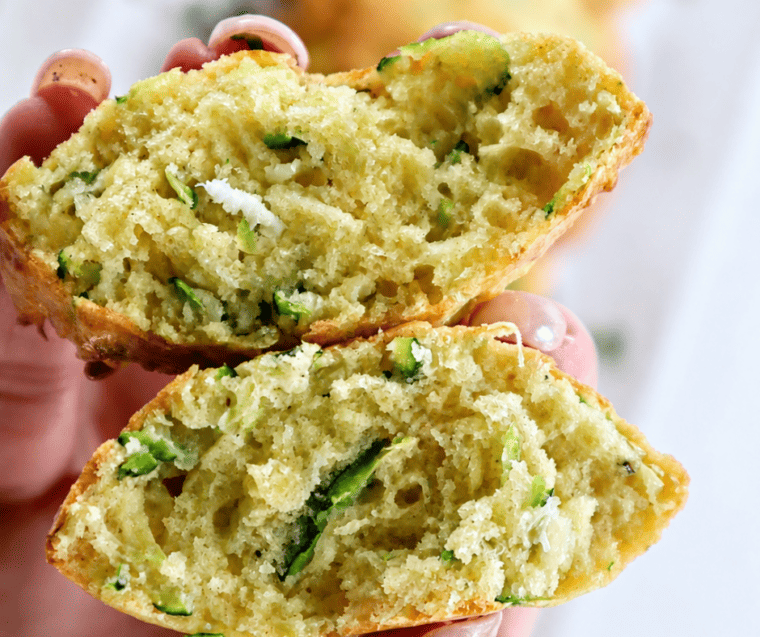 Hand holding an air fryer zucchini square cut in half to show the soft cheesy interior