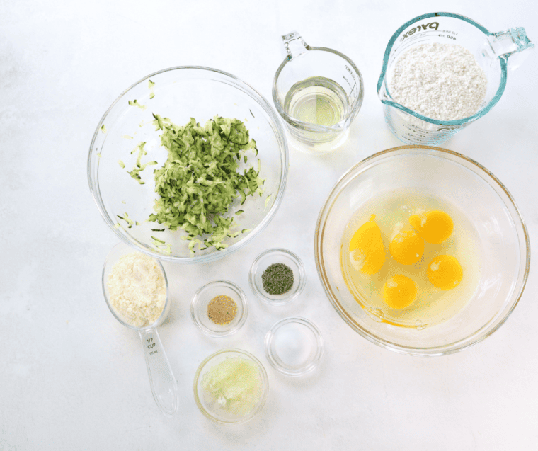 Ingredients for air fryer zucchini squares including eggs, Bisquick, Parmesan, grated zucchini, and seasonings