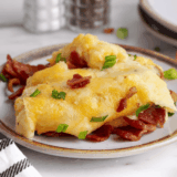Chili's loaded mashed potatoes copycat in a white baking dish topped with melted cheddar jack cheese, crumbled bacon, and sliced chives