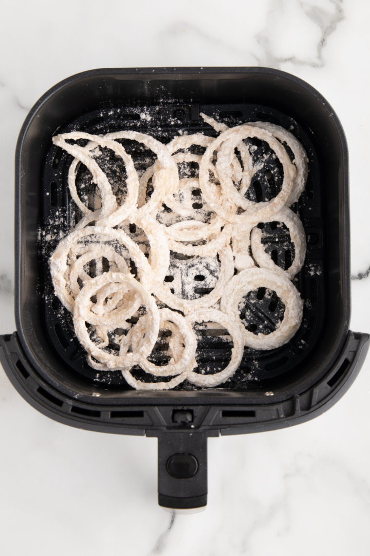 Flour coated onions in a single layer in an air fryer basket