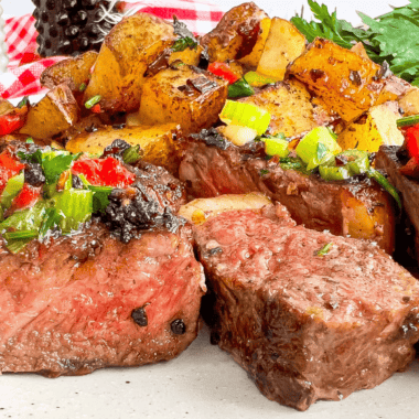 Grilled ribeye on a plate coated in homemade buttery garlic and herb seasoning with a sprig of thyme