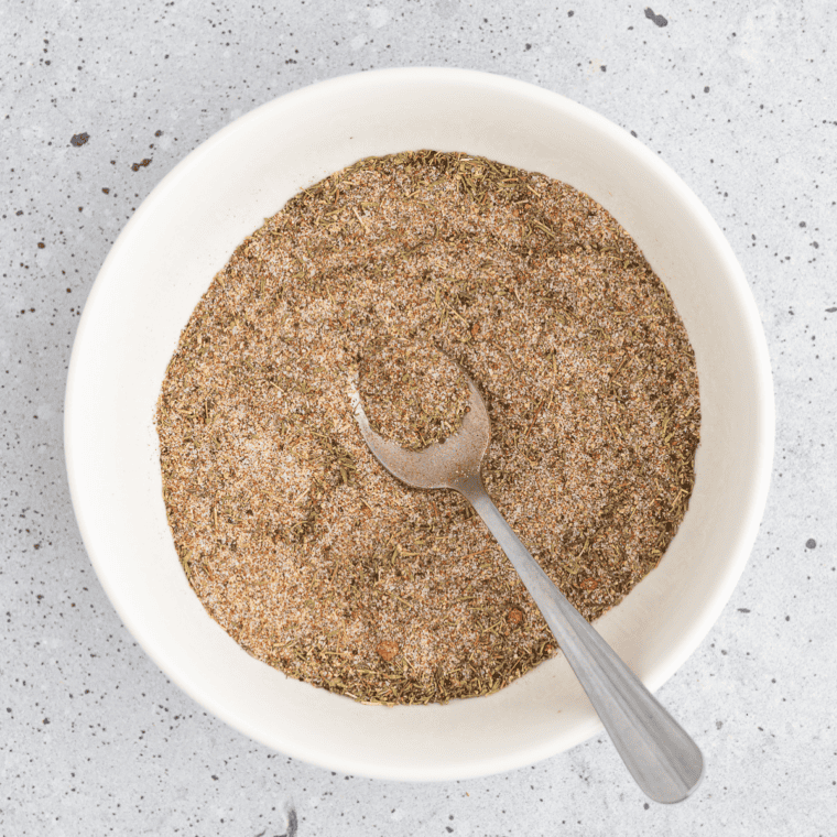 Dried lemon zest, black pepper, salt, and spices added to a small mixing bowl