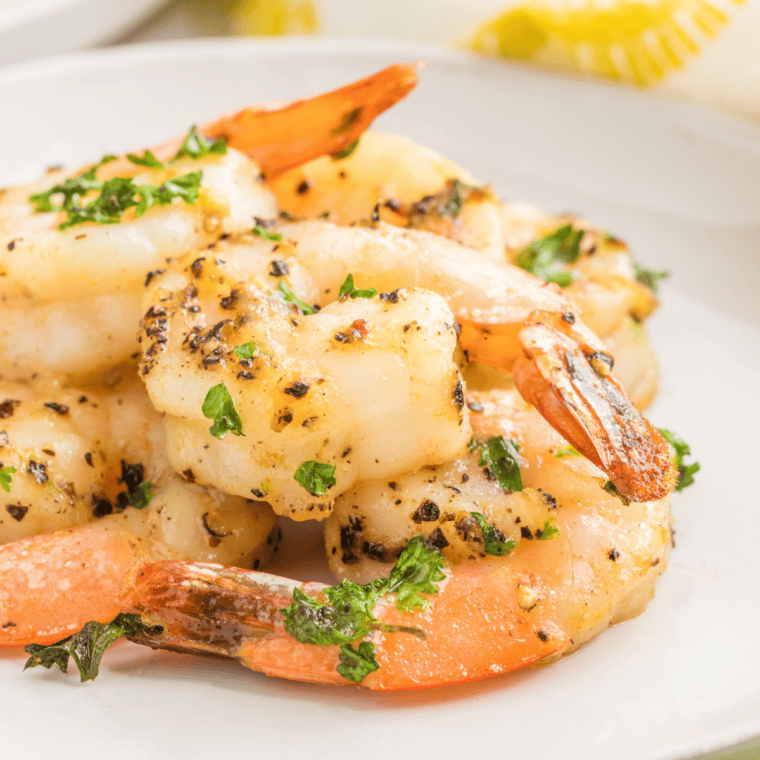 Lemon pepper shrimp arranged on a white plate with lemon wedges