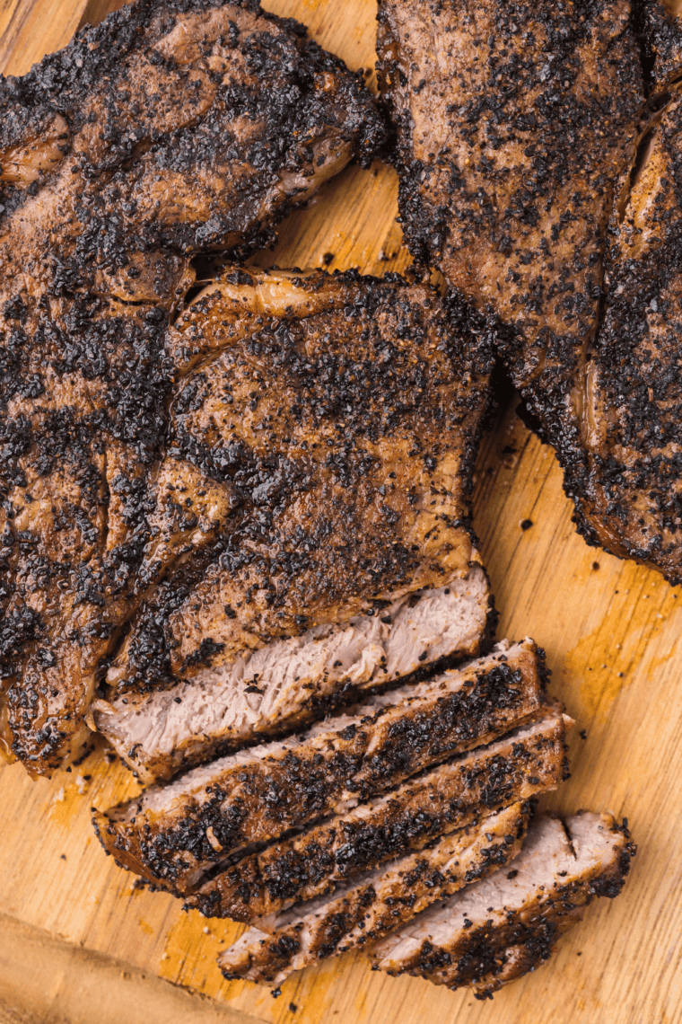 Seasoned ribeye steak searing on a hot grill with smoky woodfired garlic rub crust
