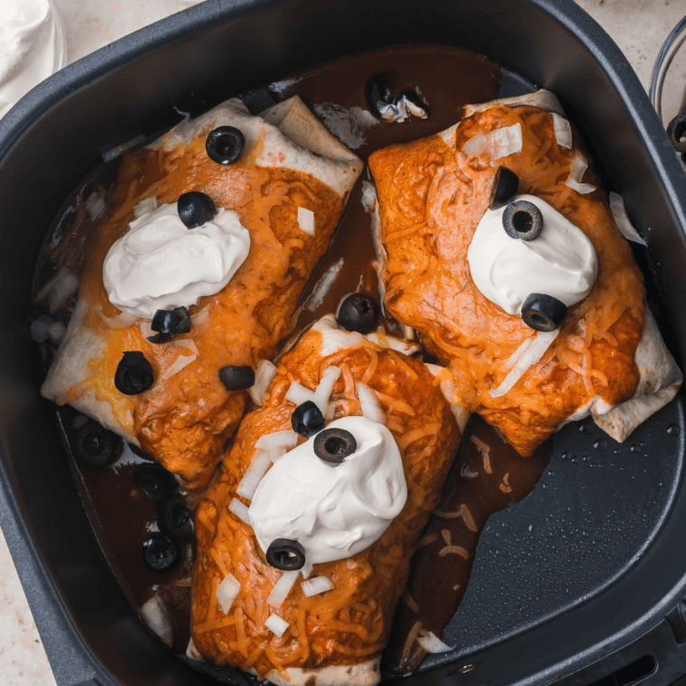 Assembled tacos crisping in an air fryer basket