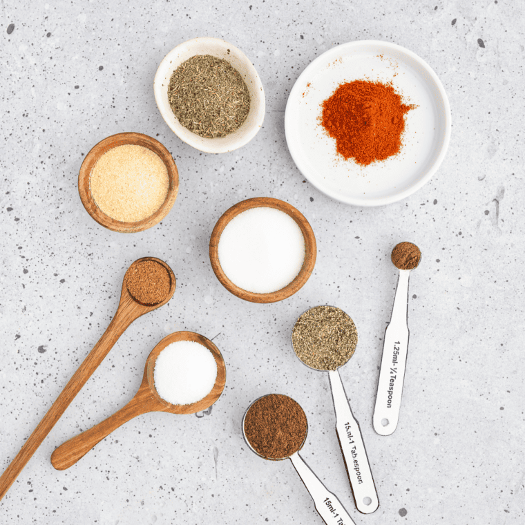 Dry milk powder, flour, cornstarch, bouillon, black pepper, sage, and thyme in small bowls on marble