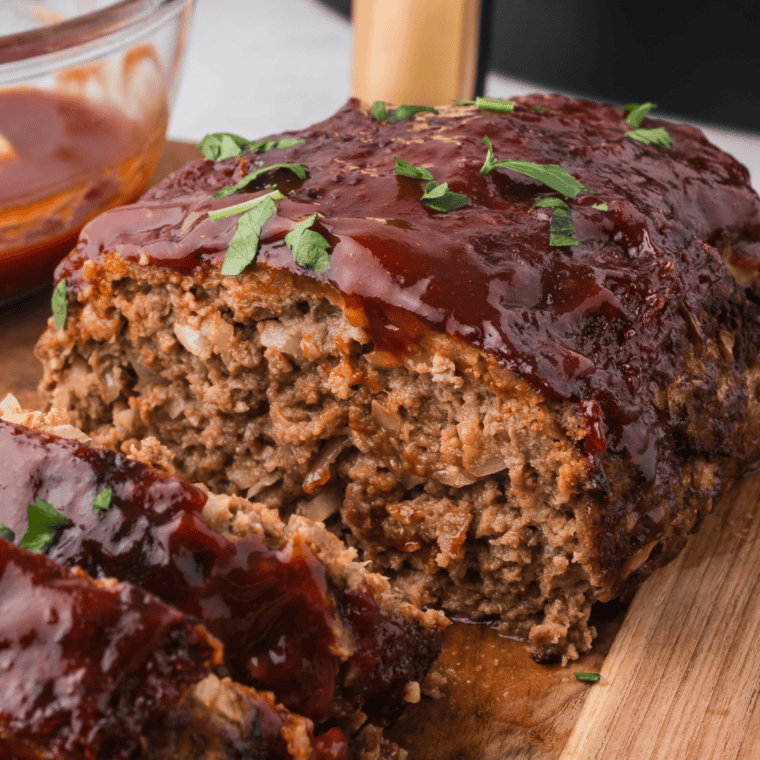 Sliced copycat McCormick meatloaf with ketchup glaze on a wooden cutting board