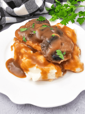 Copycat McCormick turkey gravy poured over a plate of creamy mashed potatoes