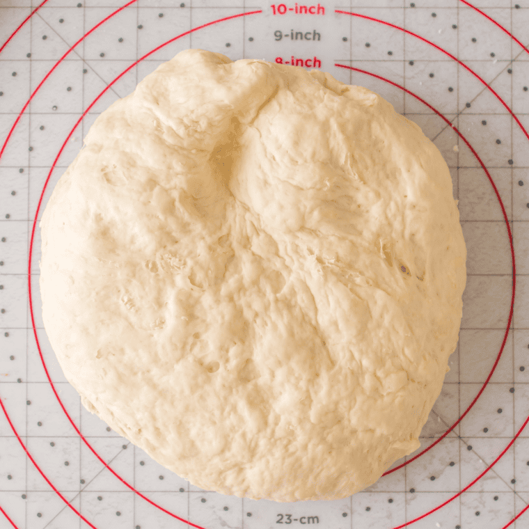 Risen pizza dough doubled in size in an oiled bowl