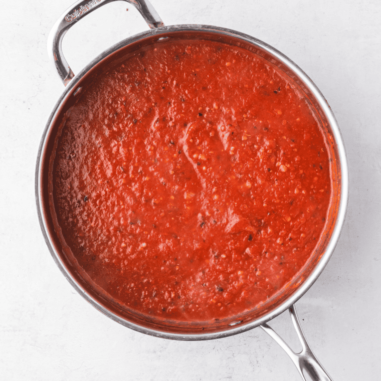 Whisking tomato paste and water together in a glass mixing bowl until smooth