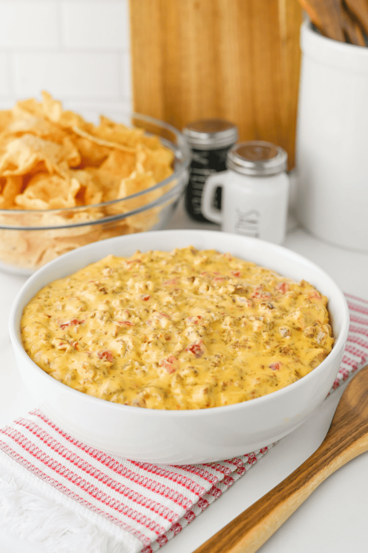 Bowl of football dip on a game day snack table with chips, wings and cold drinks