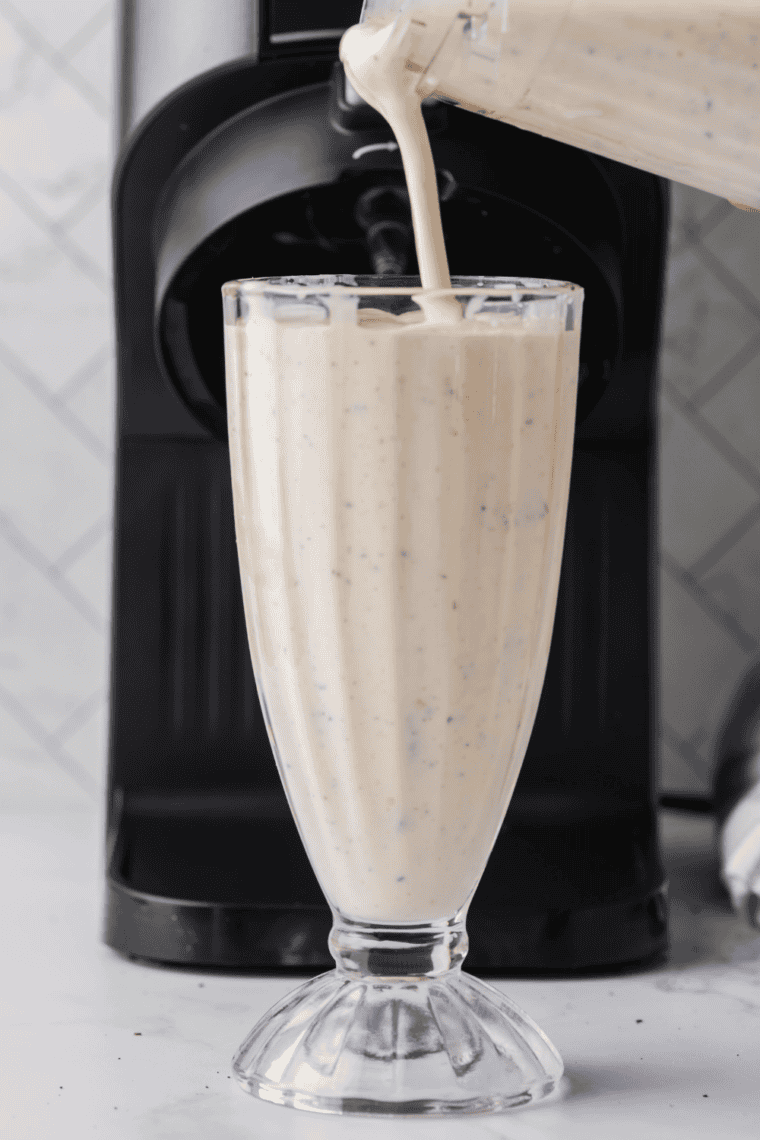 Copycat Sonic Oreo cheesecake milkshake poured into a tall glass and topped with whipped cream and Oreo crumbs