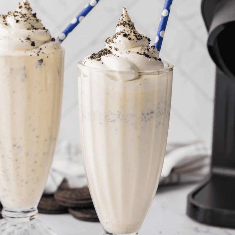 Ninja Creami Copycat Sonic Oreo Cheesecake Milkshake in a tall glass topped with whipped cream, crushed Oreos, and graham cracker crumbs