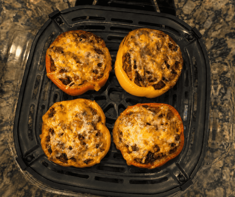 Ninja Crispi stuffed peppers with melted Colby Jack cheese in the glass air fryer container, ready to serve
