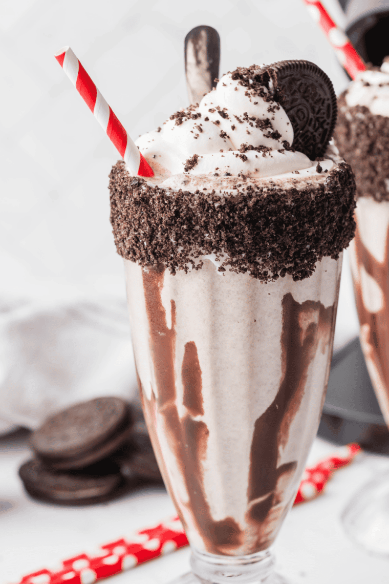 Cookies and cream milkshake made in a Ninja Slushi, poured into a tall glass with a striped straw