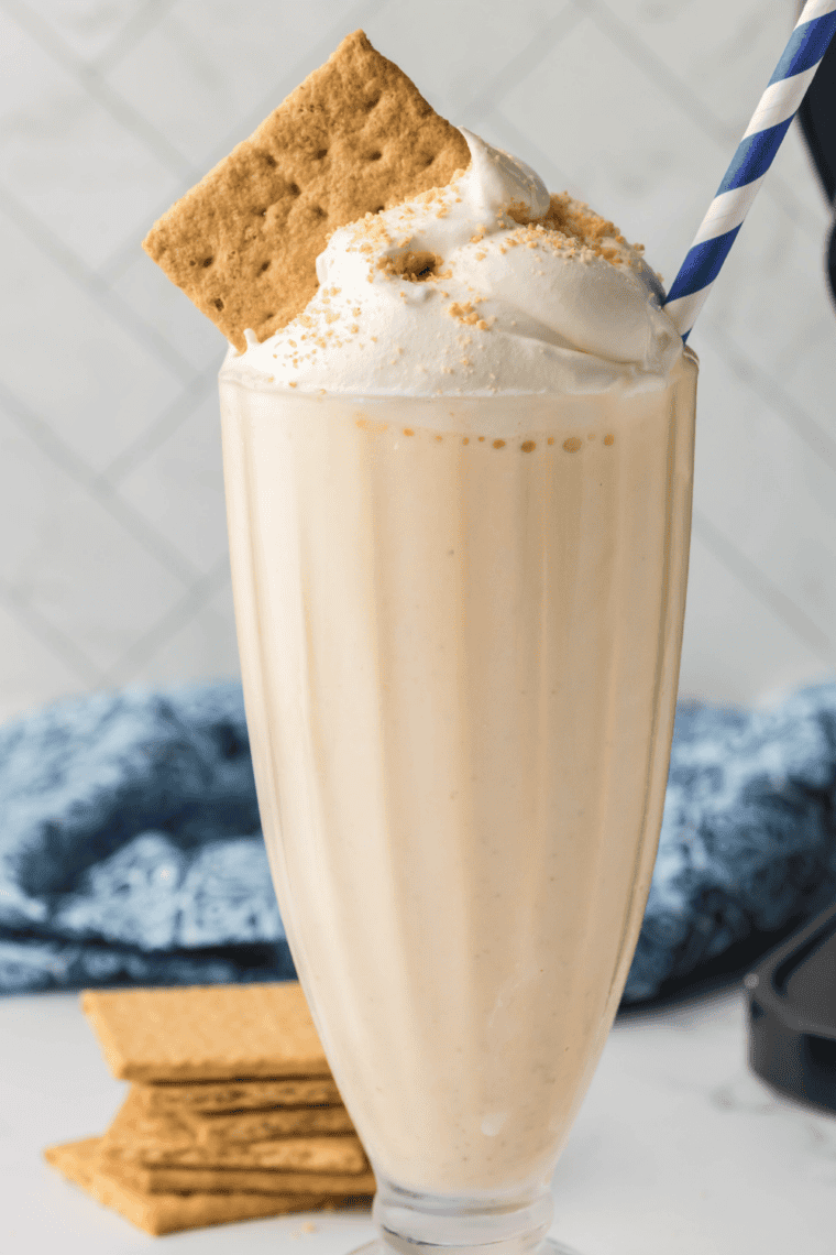 Thick vanilla milkshake made in the Ninja Slushi, poured into a tall glass with a wide straw