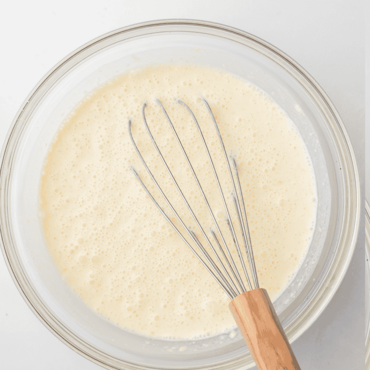 Pouring heavy cream and vanilla extract into the milk and sugar mixture in a pitcher