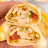 Air fryer chicken snack wrap cut in half showing shredded chicken, melted cheddar, and ranch inside a crispy golden tortilla